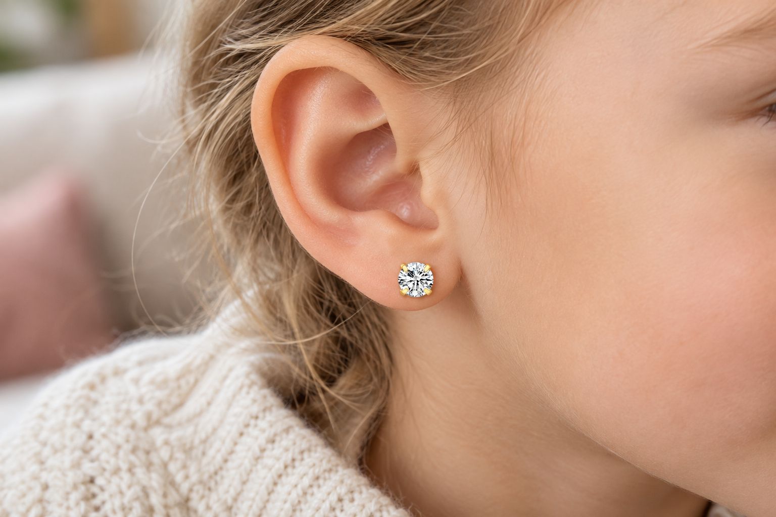 Close-up of gold flat back stud earring worn on a child's ear