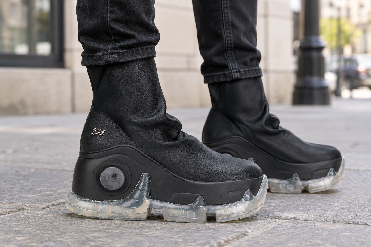 Man wearing black platform boots on a city pavement
