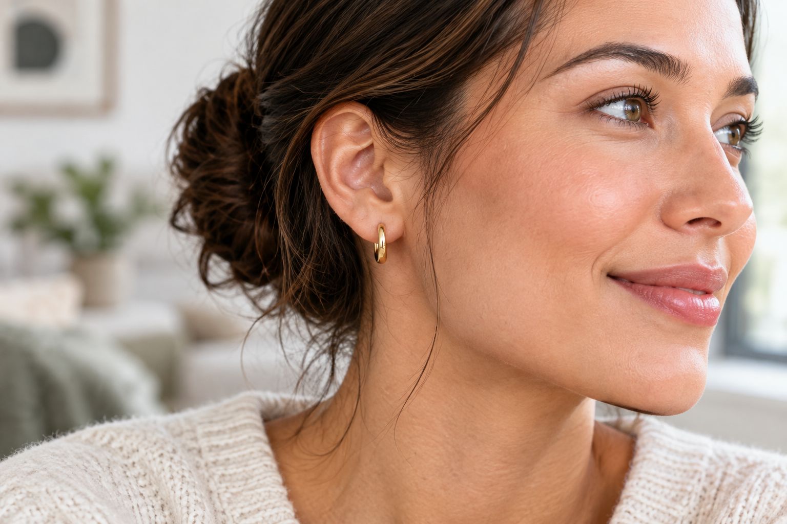 Close-up of a gold-tone hoop earring worn in an ear.