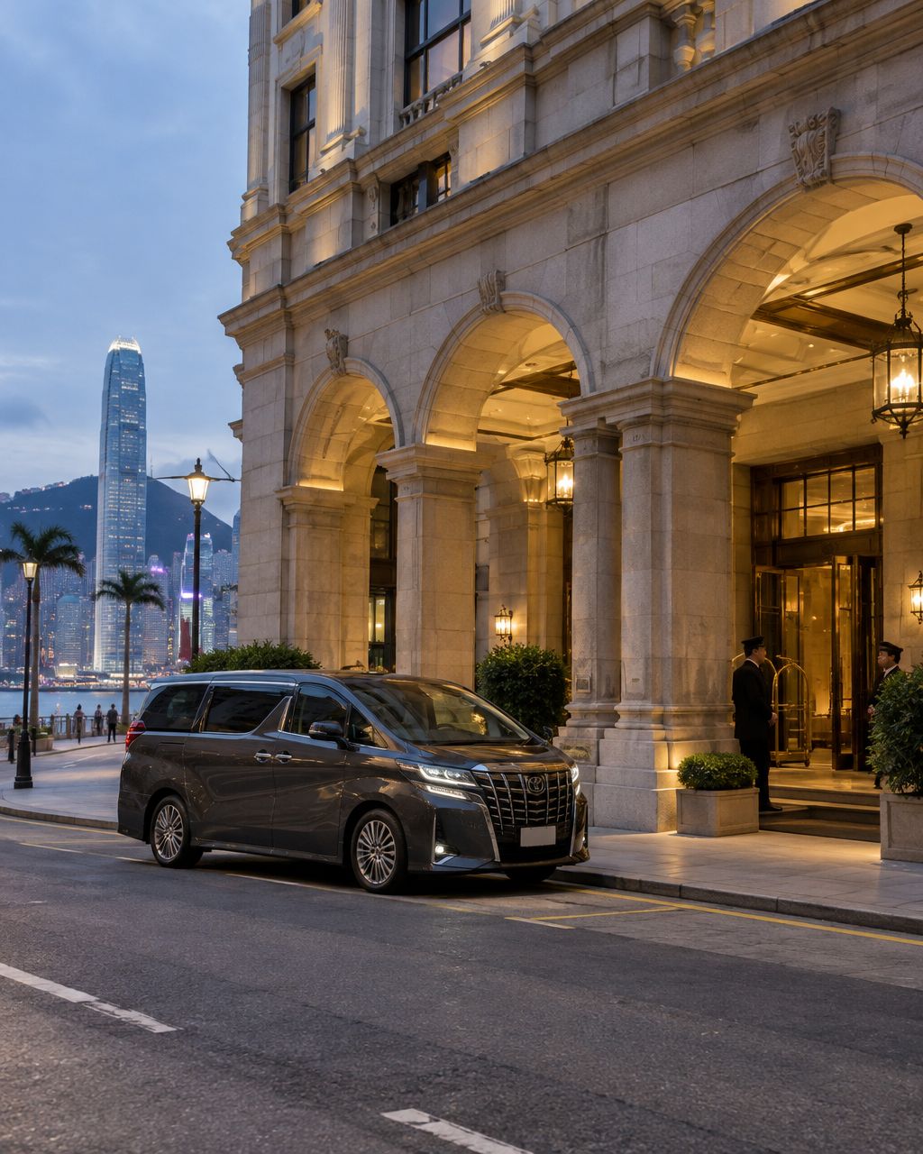 A dark grey Mayline MPV waiting under the stone arches of The Langham Hong Kong's Peking Road entrance at dusk