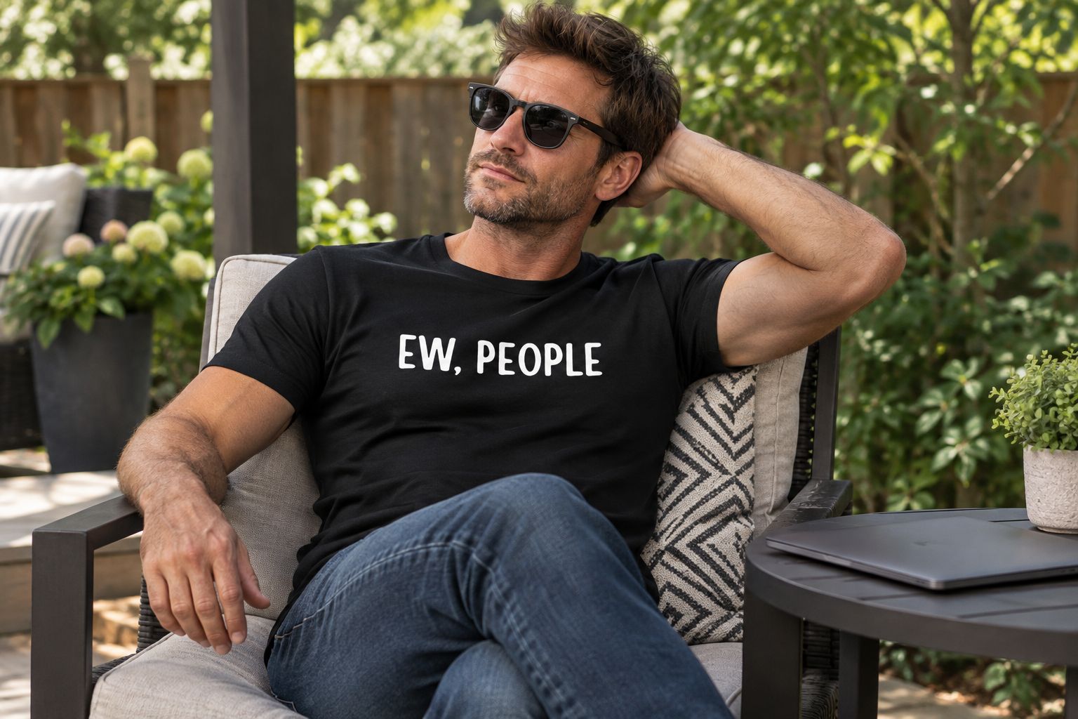 An adult wearing the Ew, People T-shirt while relaxing on a backyard patio