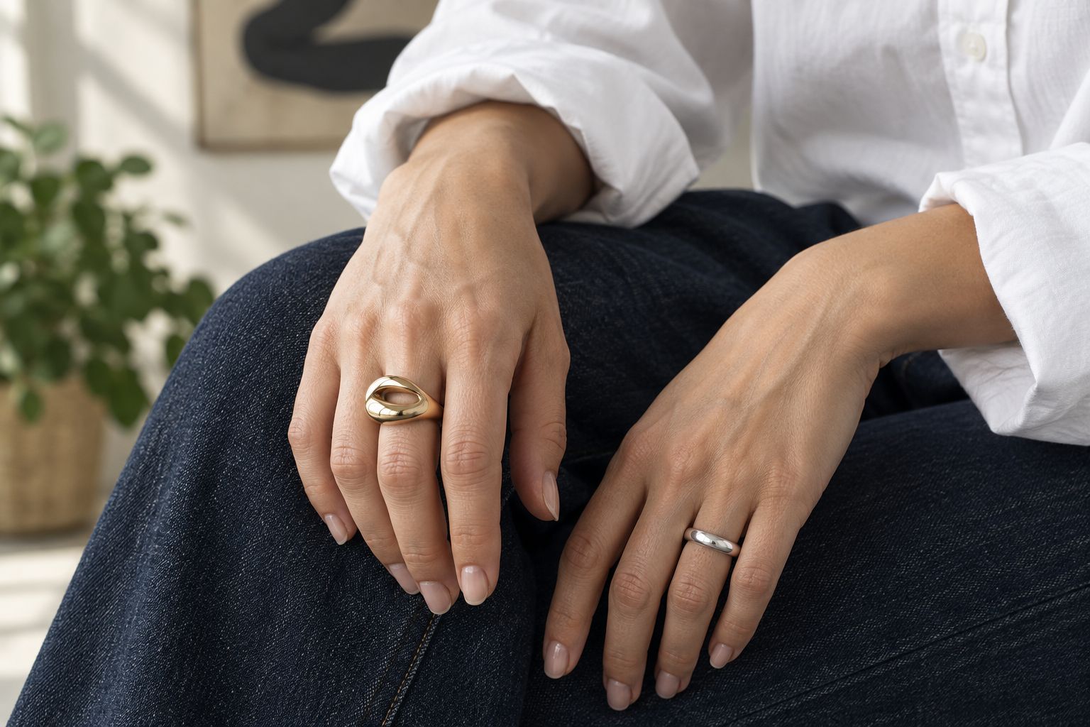 Gold-tone statement ring and silver-tone band worn on separate hands with denim and a white shirt