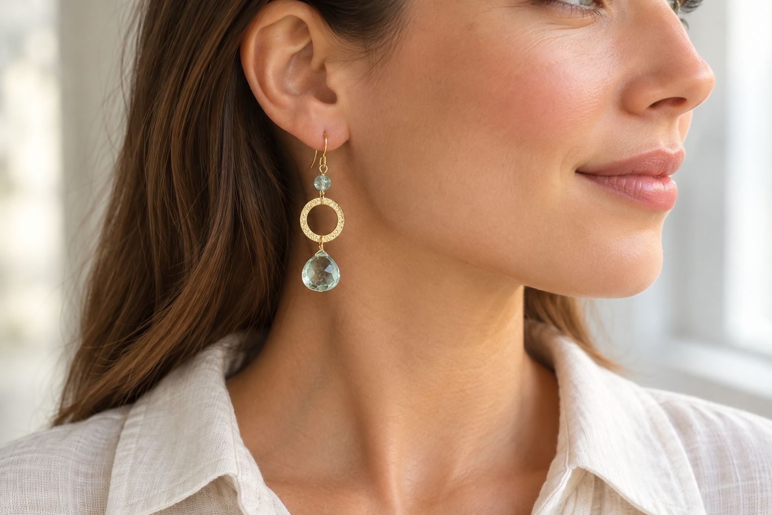Gold gemstone drop earring worn with hair tucked behind the ear