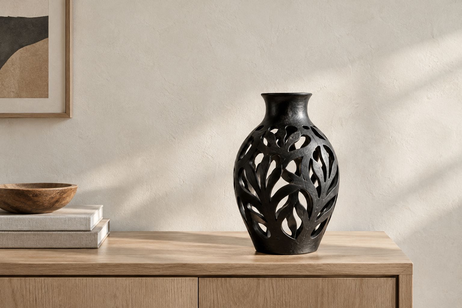 Pierced black ceramic vase displayed empty against a light wall