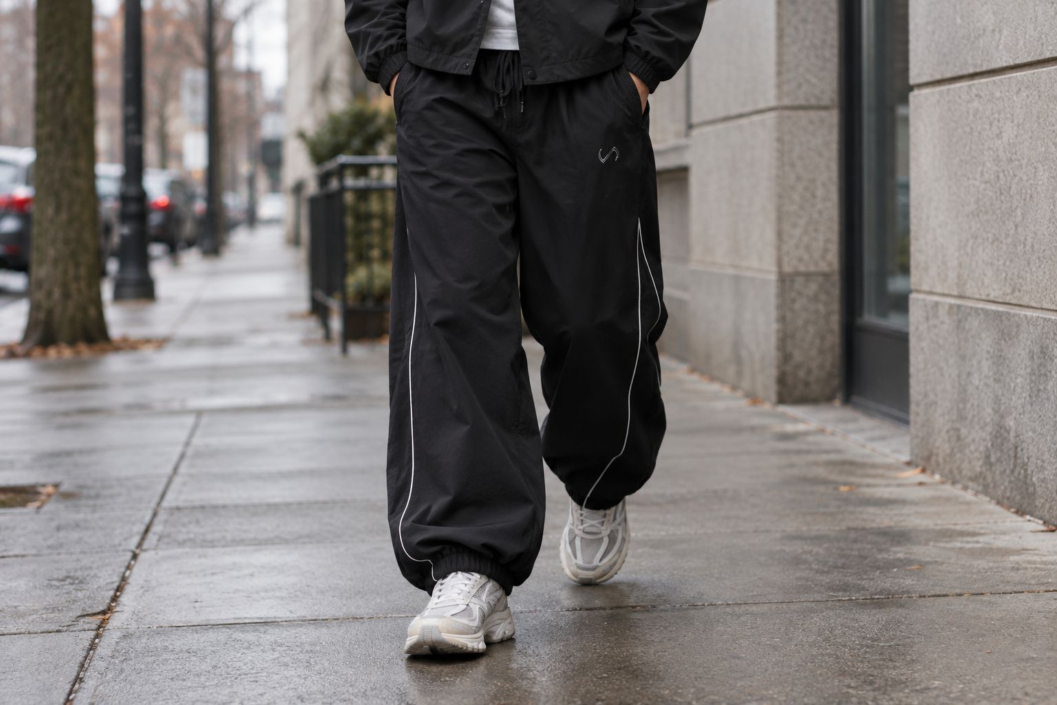 Person wearing baggy track pants walking on a city sidewalk