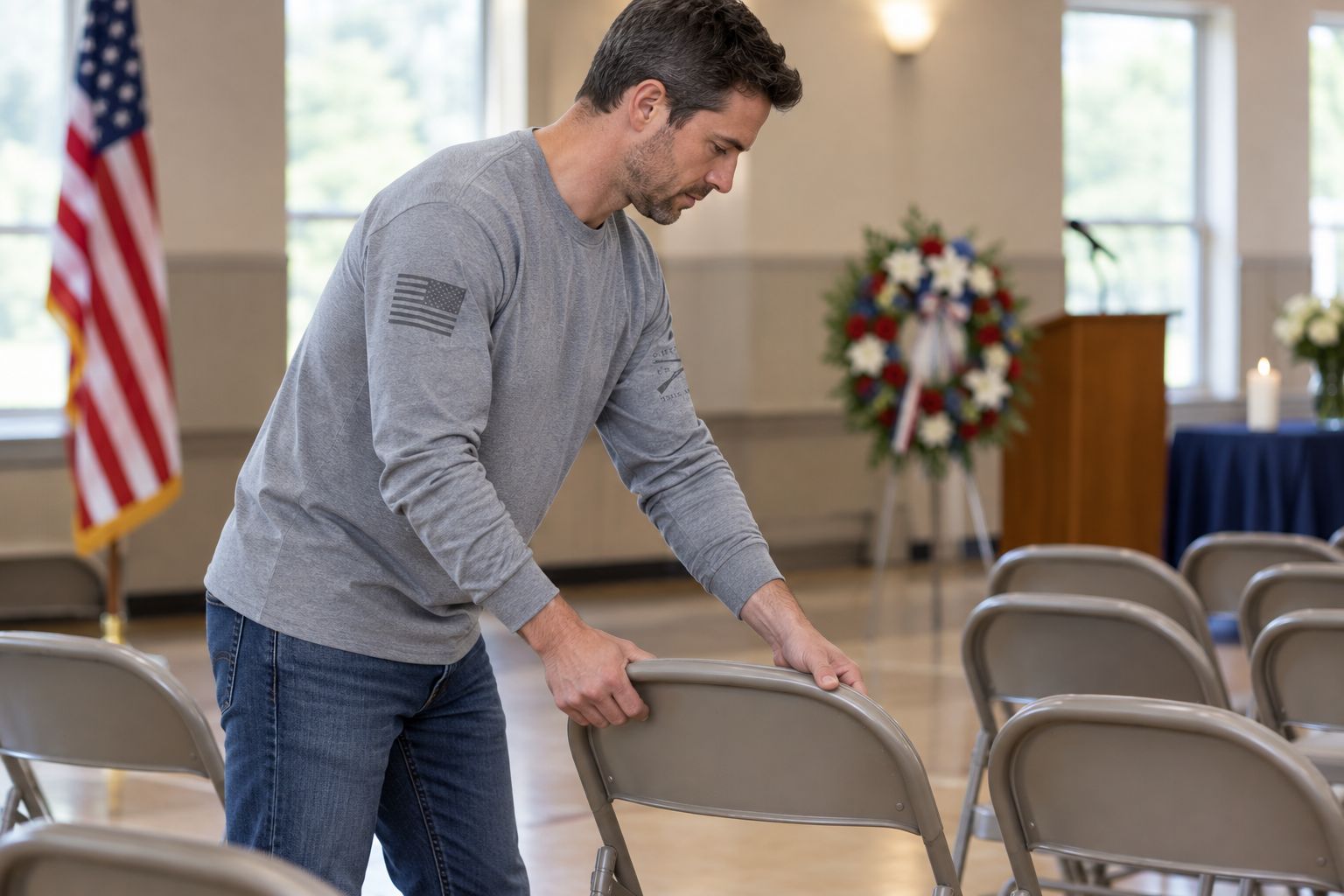Volunteer wearing a long-sleeve shirt while arranging chairs before a community remembrance gathering