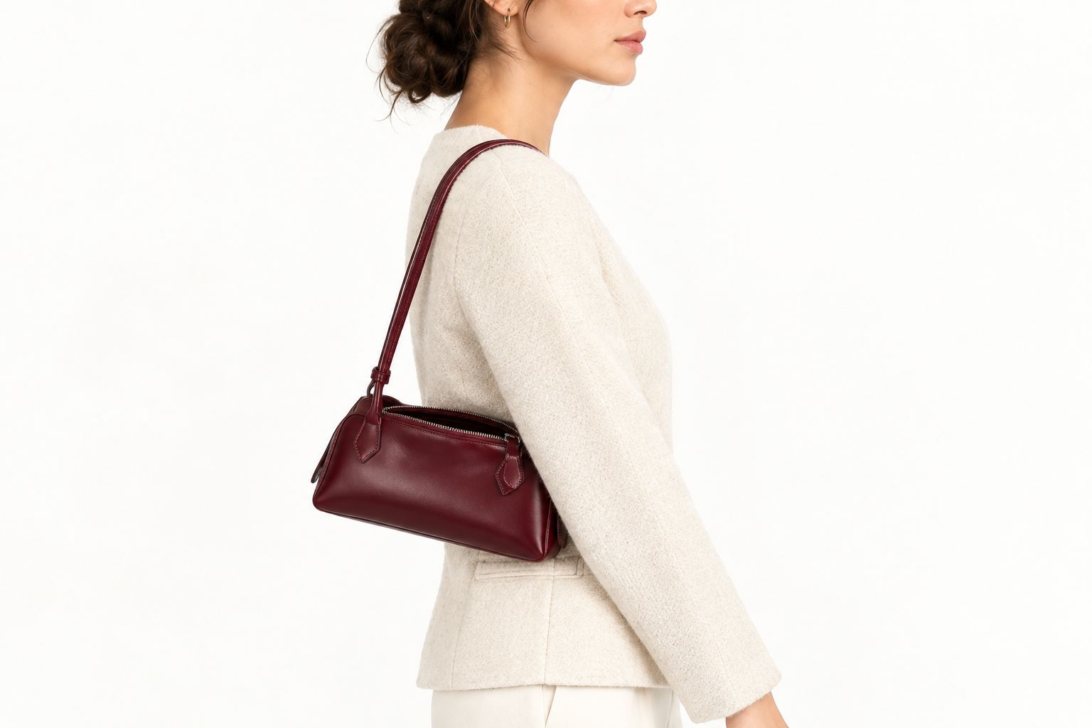 Side view of a small shoulder bag worn over a jacket with the opening visible