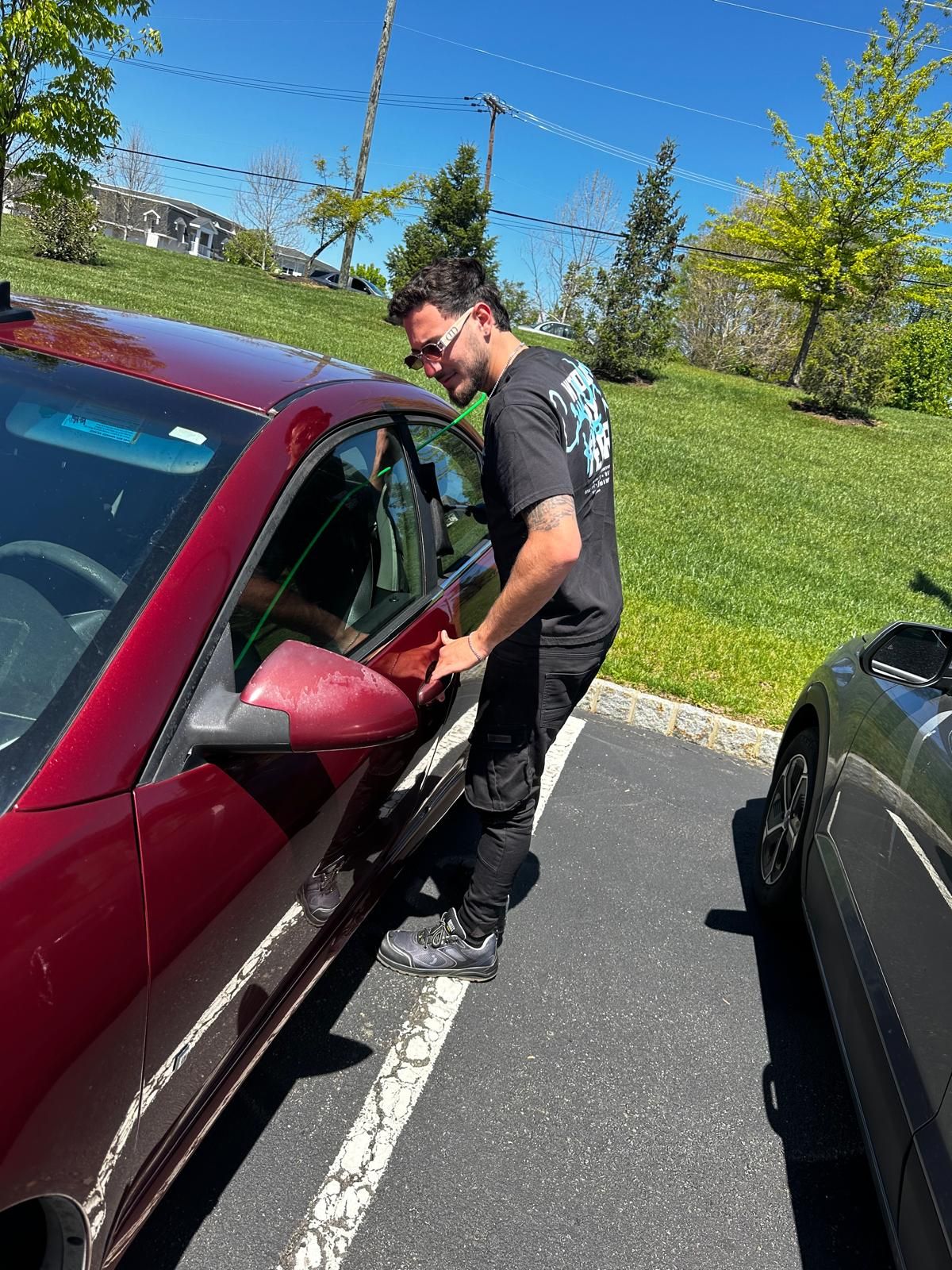 Person working beside the driver's door of a parked car