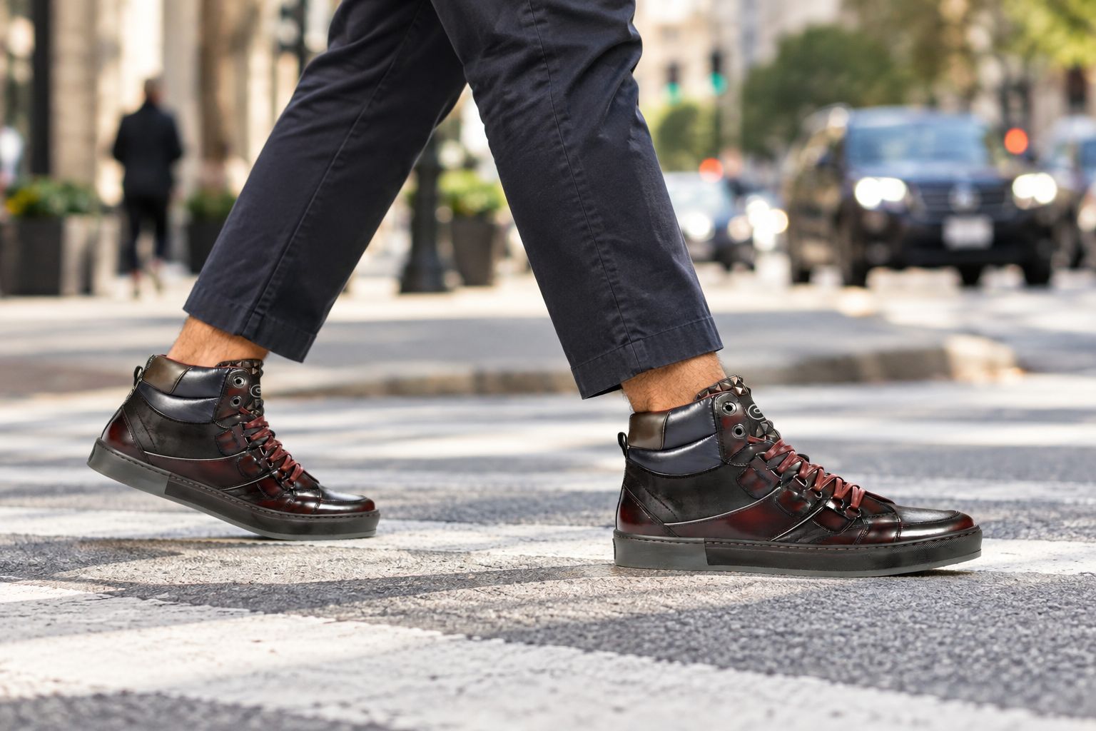 Man wearing a burgundy zippered high-top sneaker crossing a city street