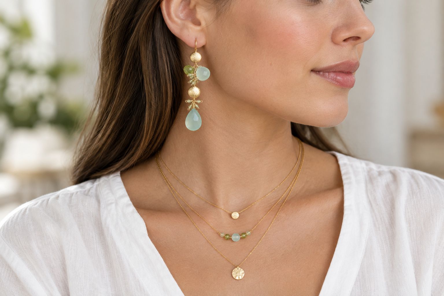 Gemstone drop earrings worn beside simple necklace layers and an open neckline