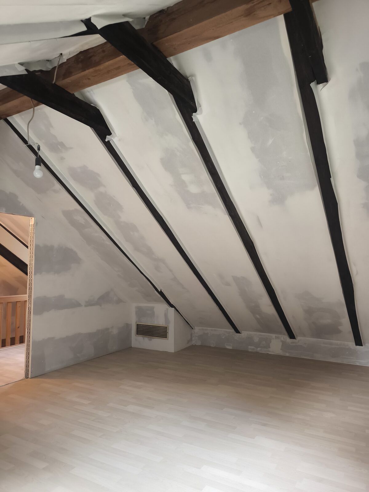 Altbausanierung mit Trockenbau an Dachschrägen und sichtbaren Holzbalken