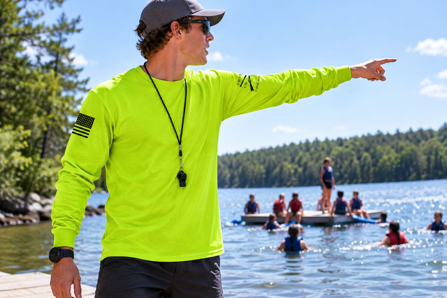 Camp counselor wearing a safety green long sleeve shirt beside a lake