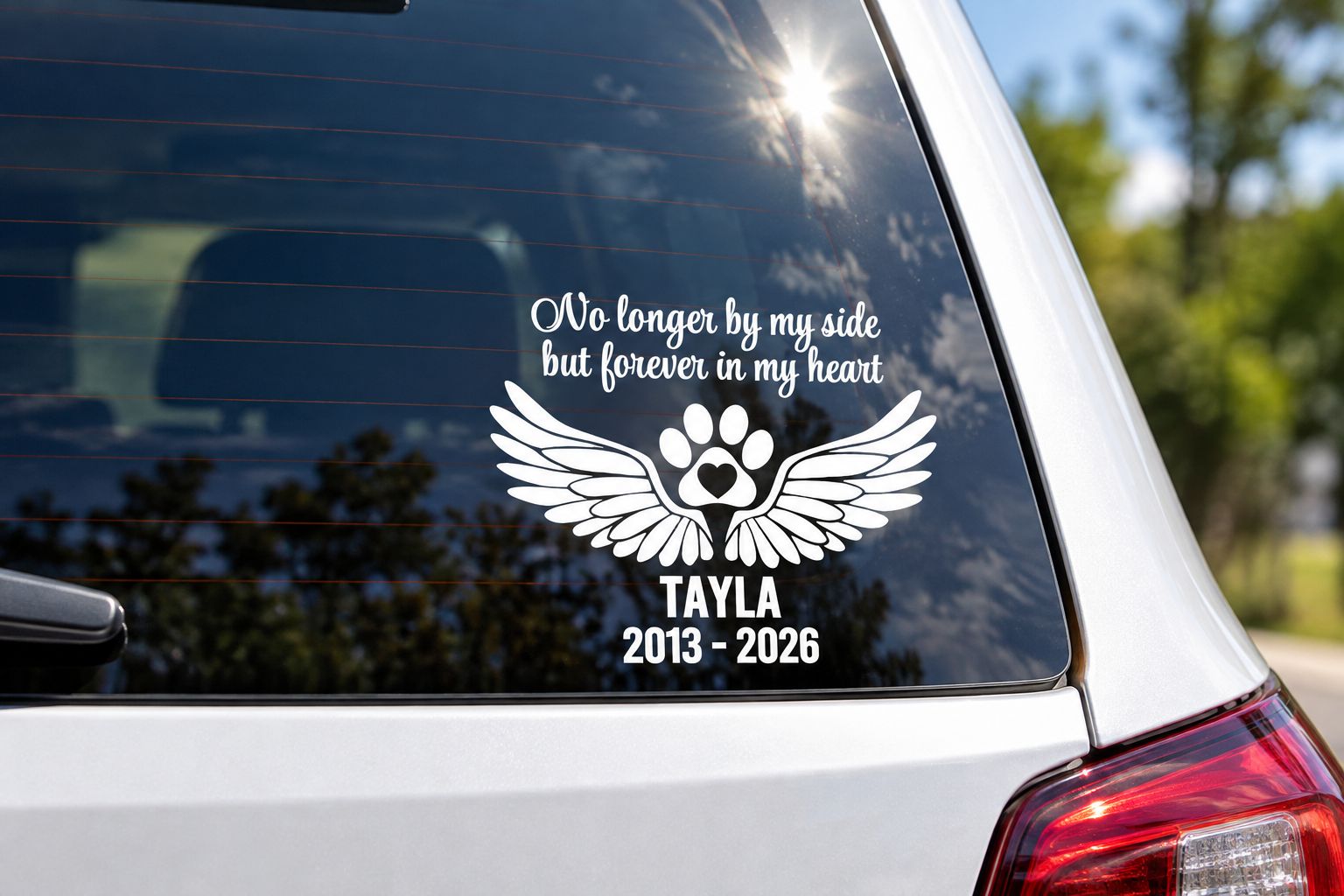 Pet memorial decal with wings and paw print applied to a car rear window