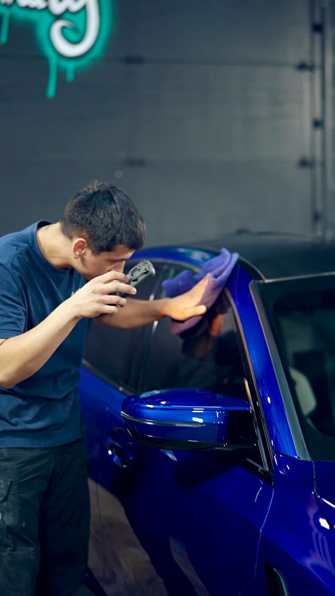 Detailer working on a blue car at Klean Detail