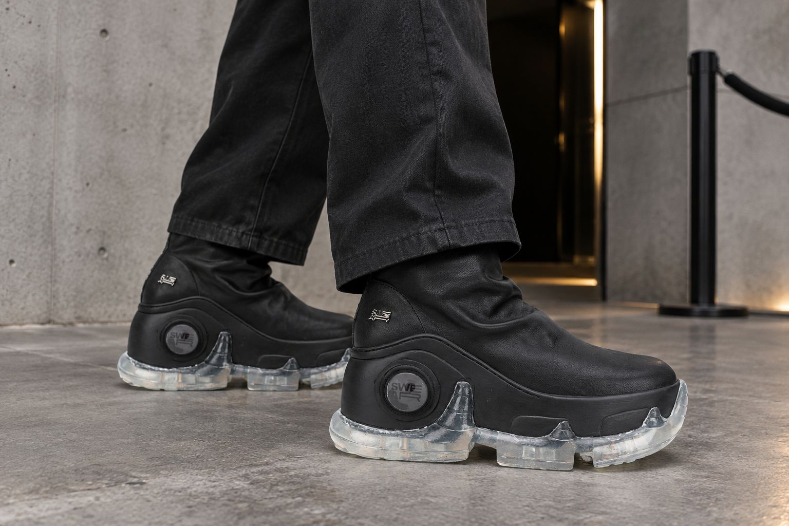 Man styling black platform boots with relaxed dark trousers