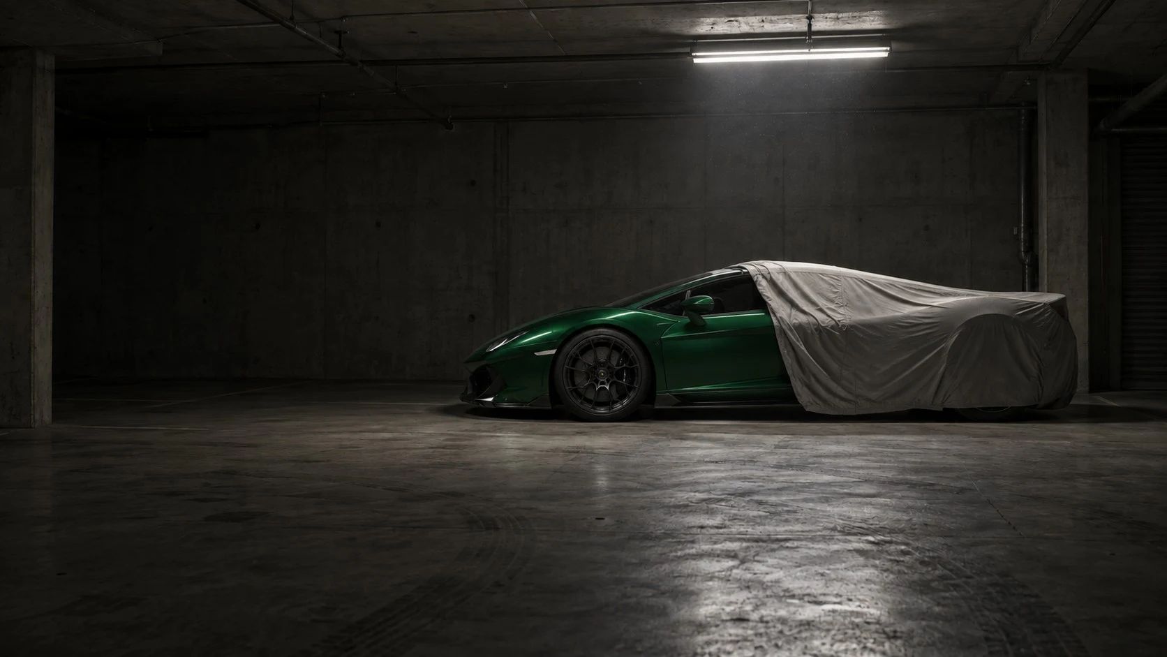 A green Porsche revealed from beneath a cover in a private garage