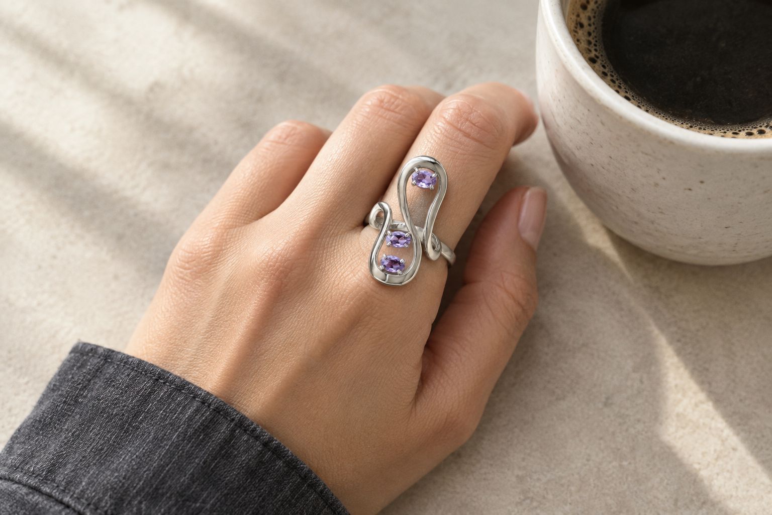 A sculptural lavender-stone ring worn with a charcoal shirt cuff