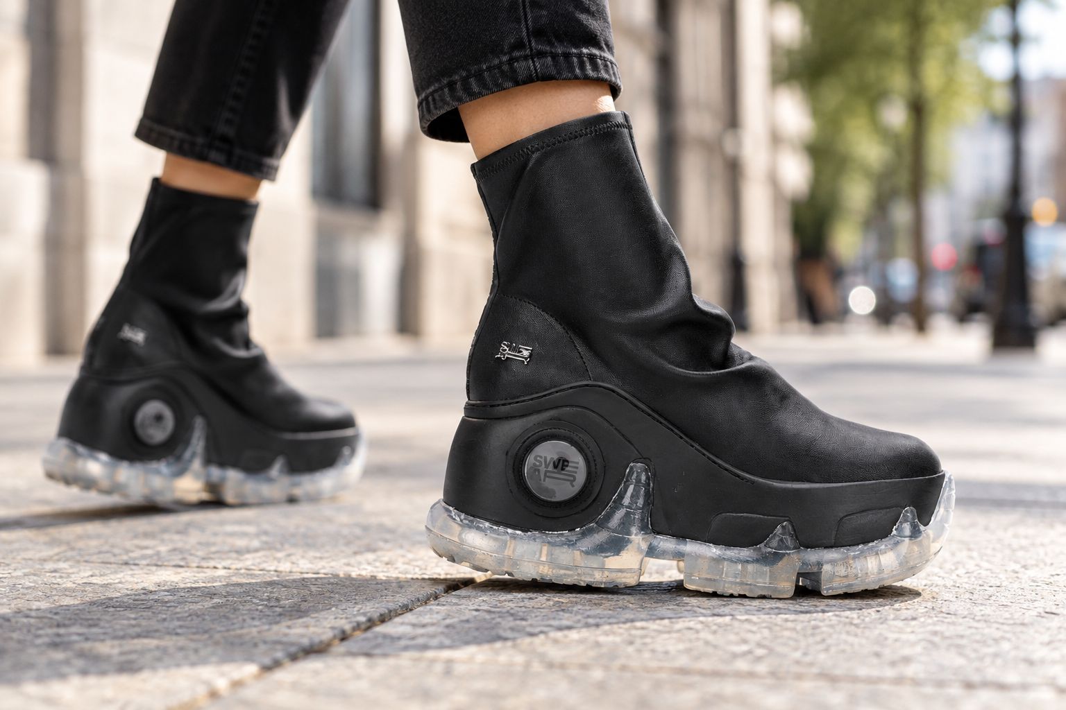 Black vegan platform boot worn mid-stride on a city pavement
