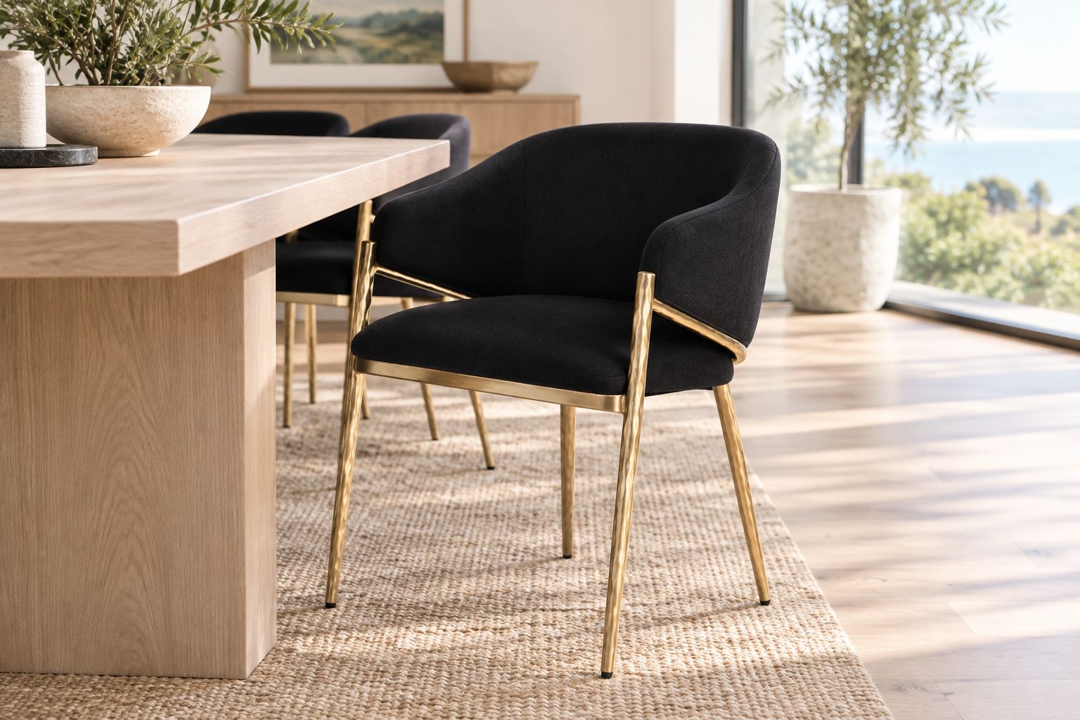 Black upholstered dining armchair beside a pale timber table with space behind it