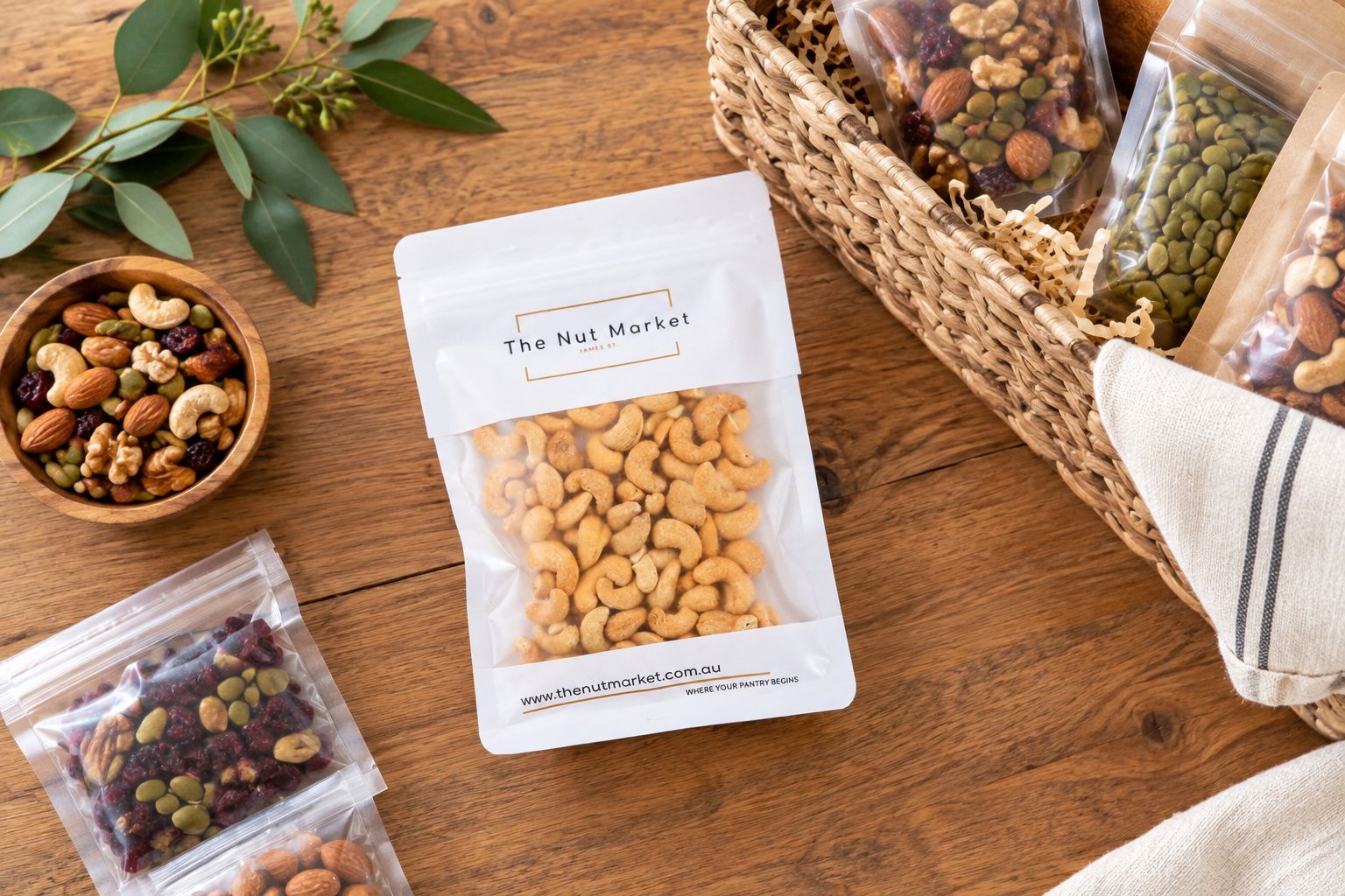 Nut Market salted cashews pack beside a gift hamper being assembled
