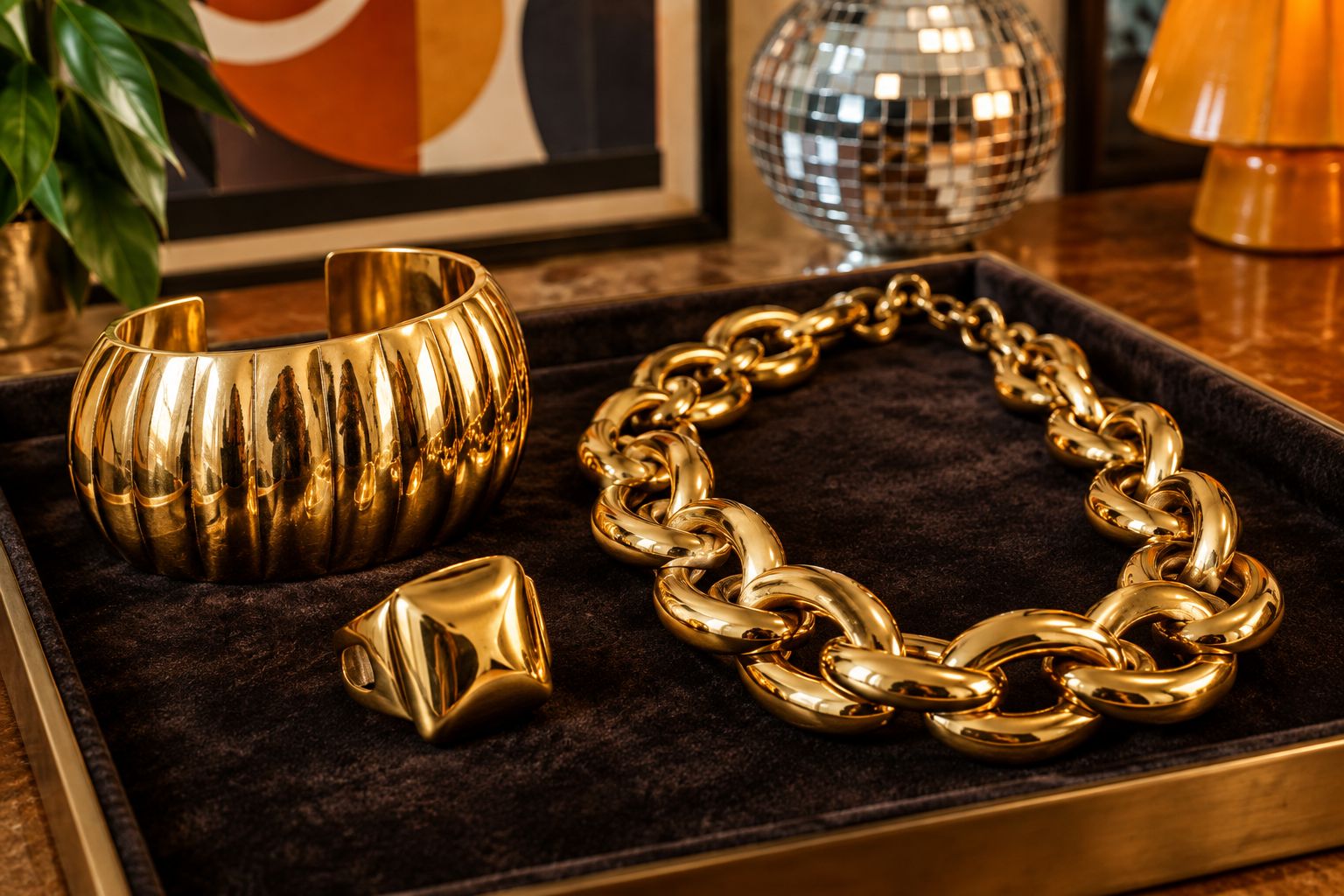 Heavy gold-tone cuff, chain necklace, and cocktail ring from the disco era displayed on velvet