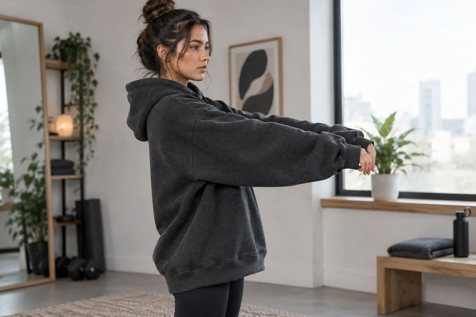 Side view of an athlete checking sleeve coverage and hem position in an oversized hoodie.